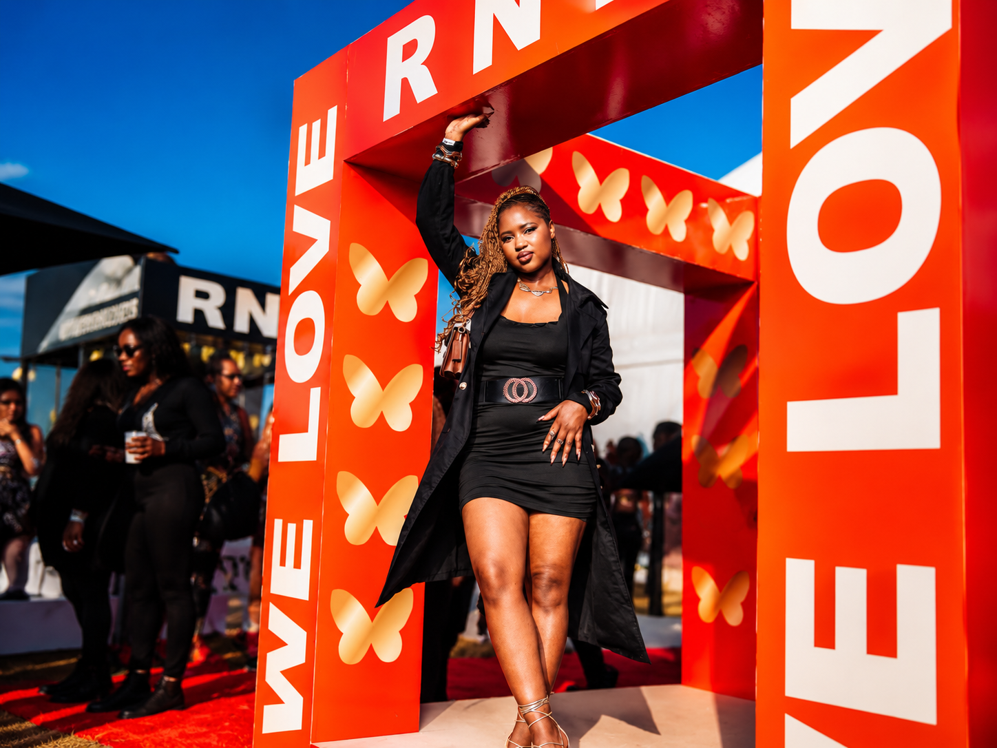 Guest posing beneath a bright orange RNB LOVE event arch