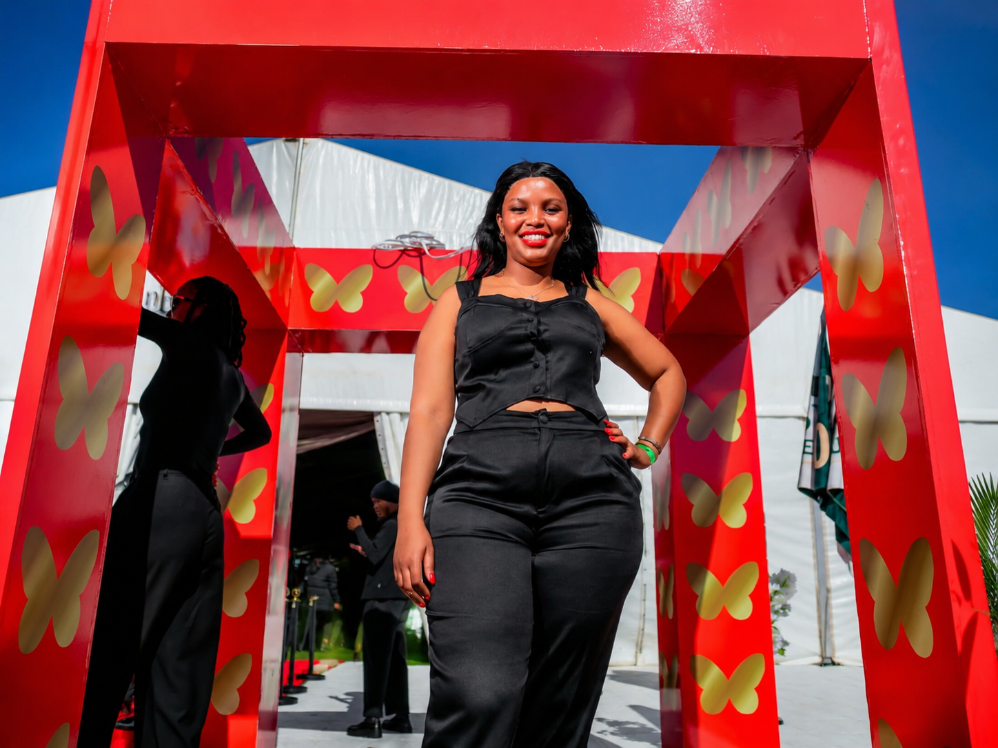 Guest walking through a red butterfly archway at an outdoor event