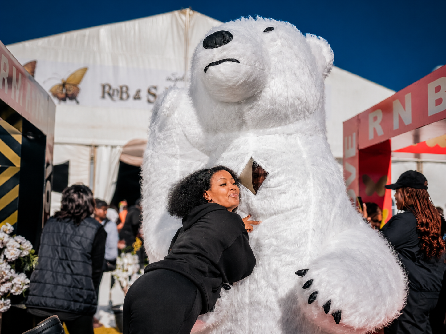 Guest posing beside a giant white polar bear mascot at an event